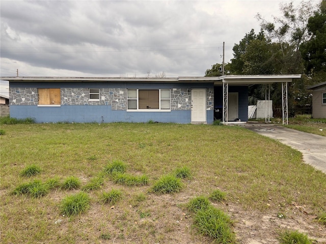 single story home featuring a carport, concrete block siding, driveway, and a front lawn