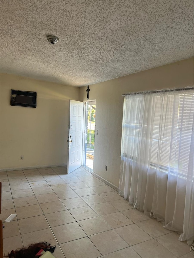 1606 26th St, Orlando, FL 32805 - empty room featuring an AC wall unit, light tile patterned floors, a textured ceiling, and baseboards