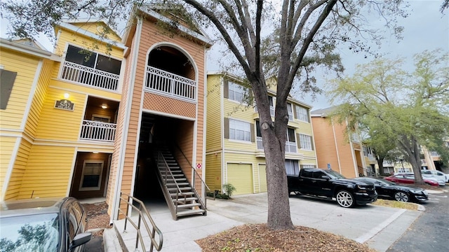 view of property featuring a garage, driveway, and stairs