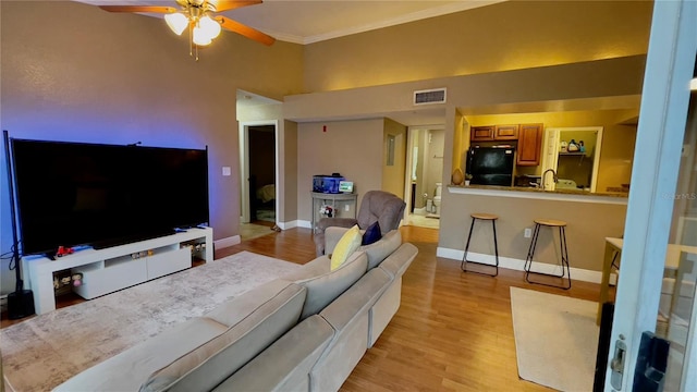 living room featuring ceiling fan, light hardwood / wood-style floors, and crown molding