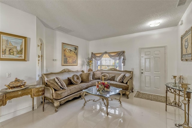 living area featuring visible vents, arched walkways, and a textured ceiling