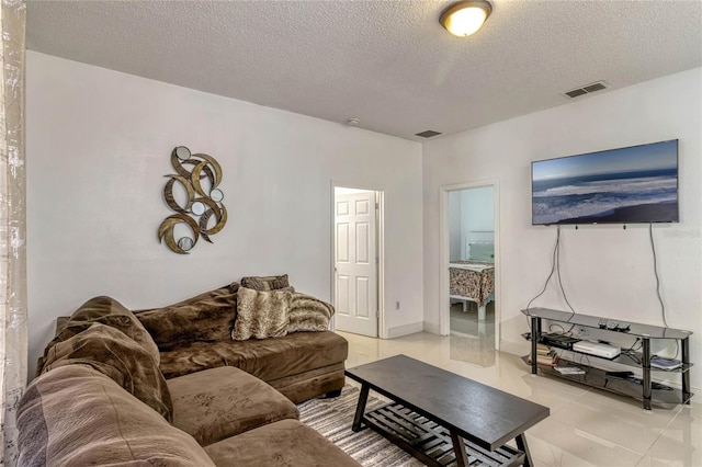 living room with visible vents, a textured ceiling, and light tile patterned floors