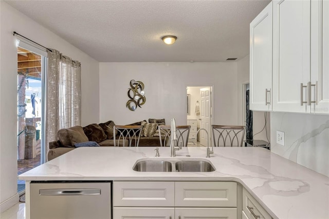 kitchen featuring open floor plan, a sink, dishwasher, and white cabinets
