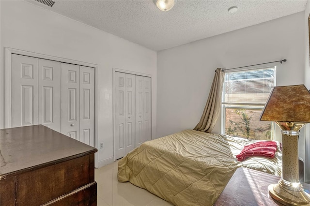bedroom featuring a textured ceiling and multiple closets