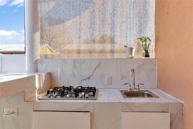 kitchen featuring stainless steel gas stovetop, light countertops, a sink, and backsplash