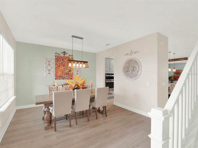 dining area with light wood-style floors, baseboards, and a wealth of natural light