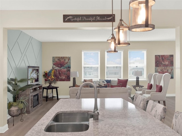 kitchen with hanging light fixtures, wood finished floors, plenty of natural light, and a sink