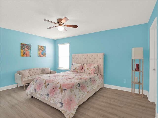 bedroom featuring ceiling fan, baseboards, and wood finished floors