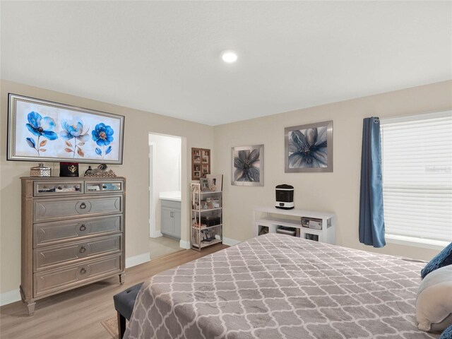 bedroom featuring light wood-style flooring, baseboards, and ensuite bathroom