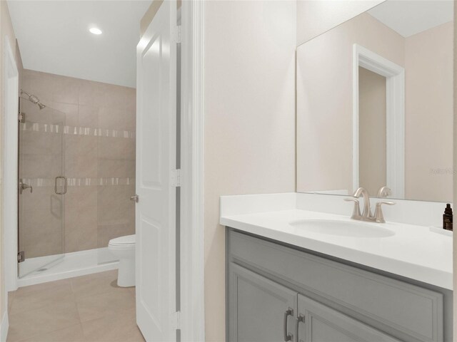 bathroom with recessed lighting, toilet, a shower stall, vanity, and tile patterned flooring