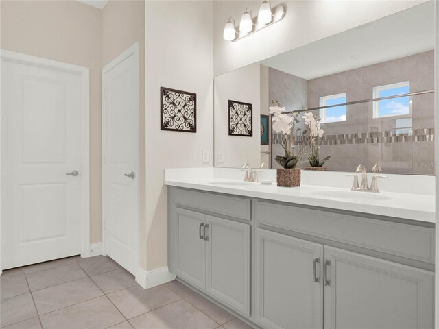 full bathroom featuring tile patterned flooring, double vanity, a sink, and walk in shower