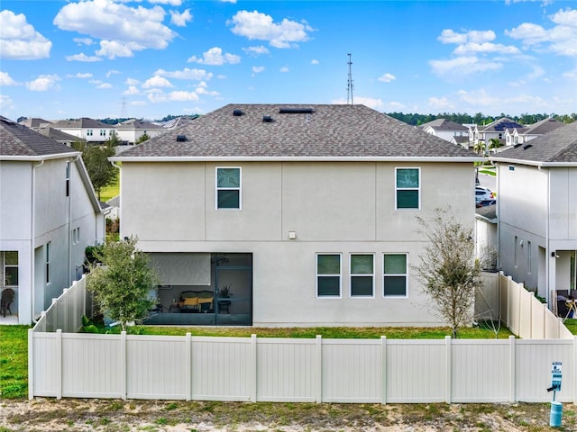 rear view of property with a residential view, fence, and stucco siding