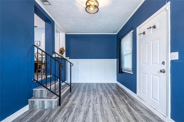 entryway featuring hardwood / wood-style flooring, crown molding, and a textured ceiling