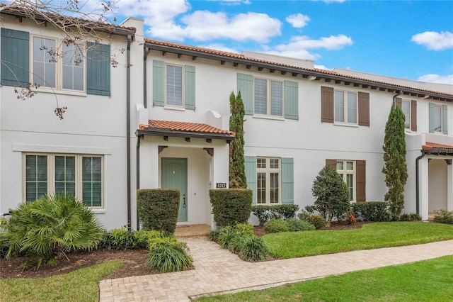 view of front of home featuring a front yard, a tiled roof, and stucco siding