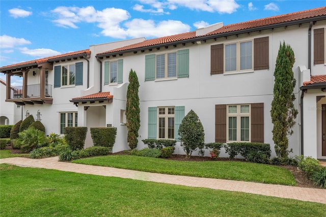 mediterranean / spanish-style house featuring a tiled roof, a front lawn, and stucco siding