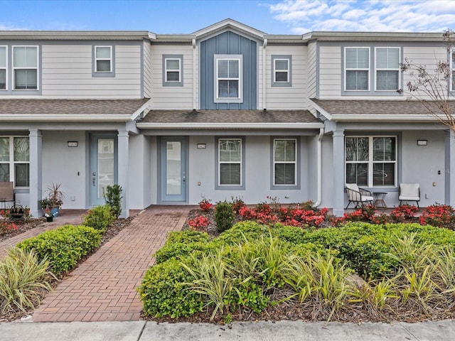 townhome / multi-family property featuring a shingled roof, board and batten siding, and stucco siding