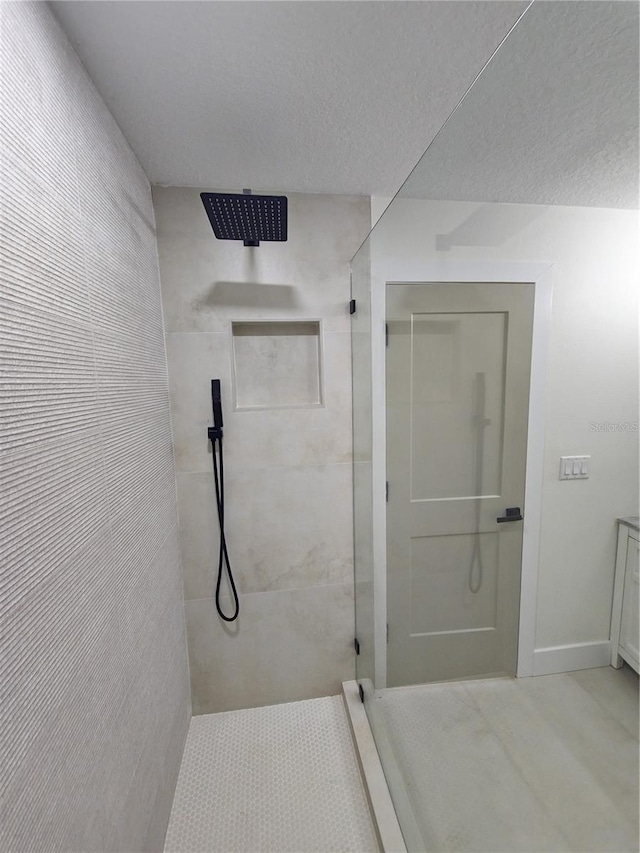 full bathroom featuring a textured ceiling, baseboards, and a walk in shower