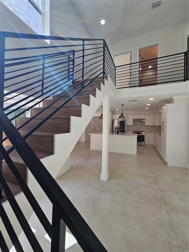 stairway with tile patterned flooring, a high ceiling, visible vents, and recessed lighting