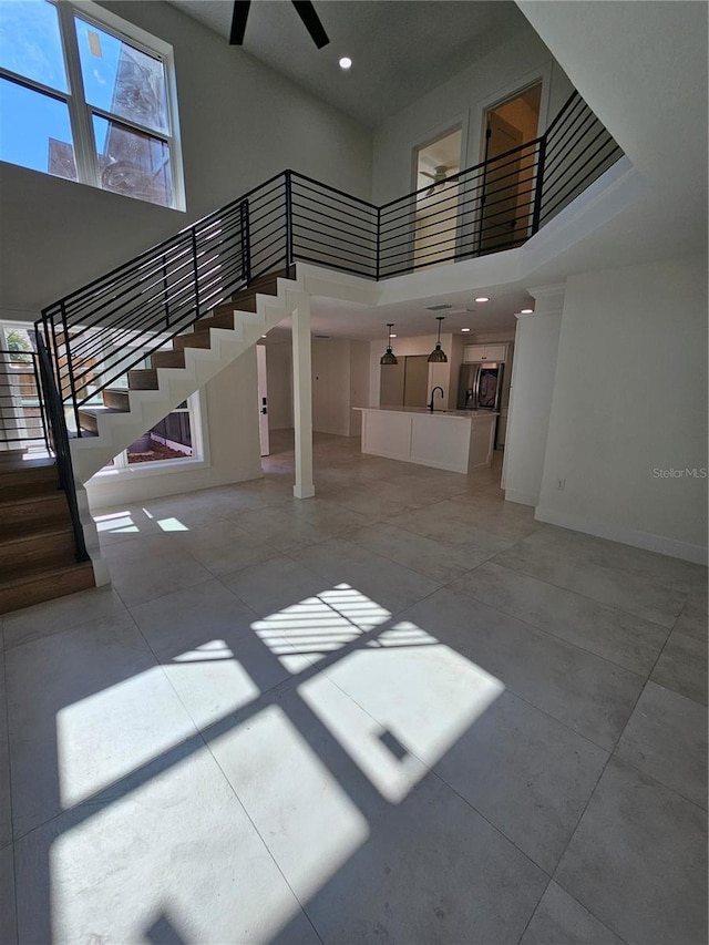 interior space featuring recessed lighting, a high ceiling, a ceiling fan, baseboards, and stairs