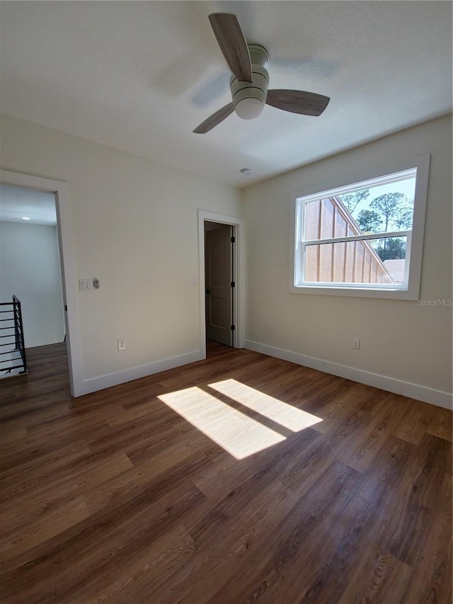 unfurnished bedroom featuring ceiling fan, baseboards, and dark wood finished floors