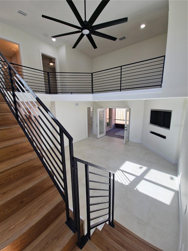 staircase with ceiling fan, a high ceiling, visible vents, and recessed lighting