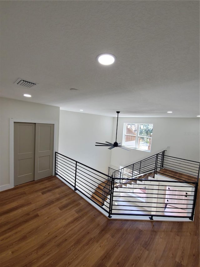 corridor featuring wood finished floors, an upstairs landing, and recessed lighting