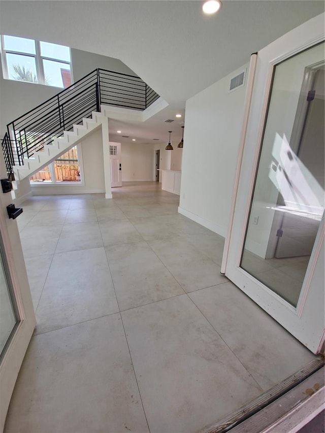 interior space with recessed lighting, visible vents, stairway, a towering ceiling, and baseboards