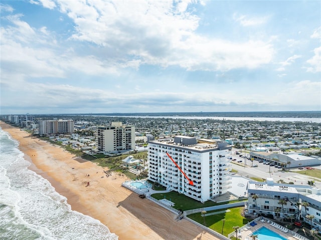 drone / aerial view featuring a view of city, a water view, and a beach view