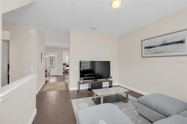 living room featuring visible vents, baseboards, and wood finished floors