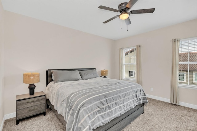 bedroom with multiple windows, baseboards, a ceiling fan, and light colored carpet