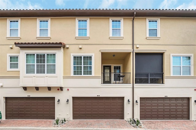 multi unit property featuring a garage, decorative driveway, and stucco siding