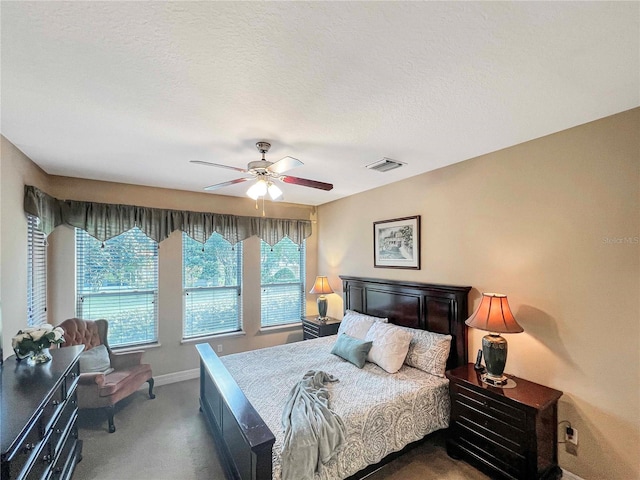 carpeted bedroom featuring ceiling fan and a textured ceiling