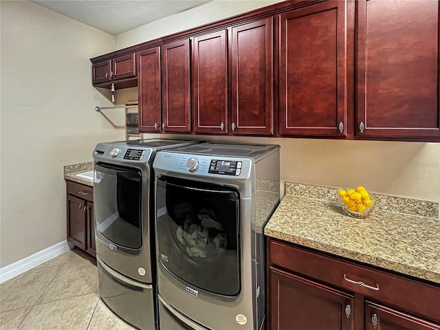 clothes washing area with light tile patterned flooring, cabinets, washer and dryer, and a textured ceiling