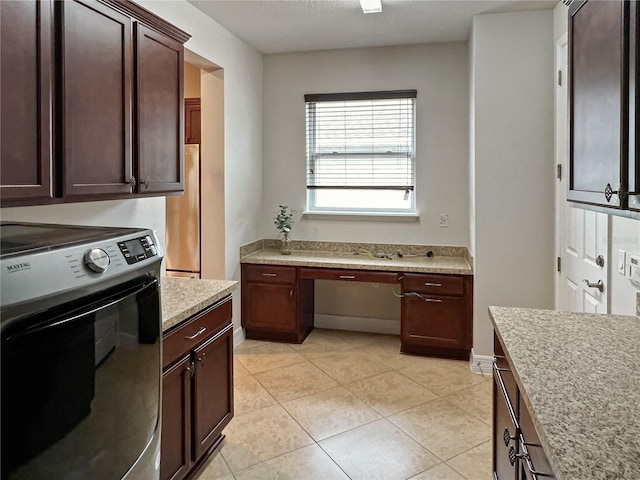 kitchen with dark brown cabinets, built in desk, wall oven, refrigerator, and light tile patterned floors