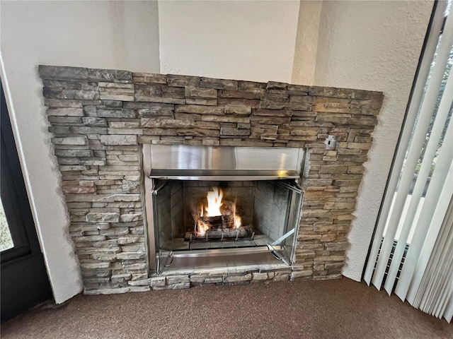 interior details with a stone fireplace and carpet