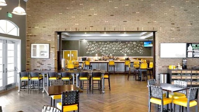 bar with a high ceiling, french doors, parquet floors, and brick wall