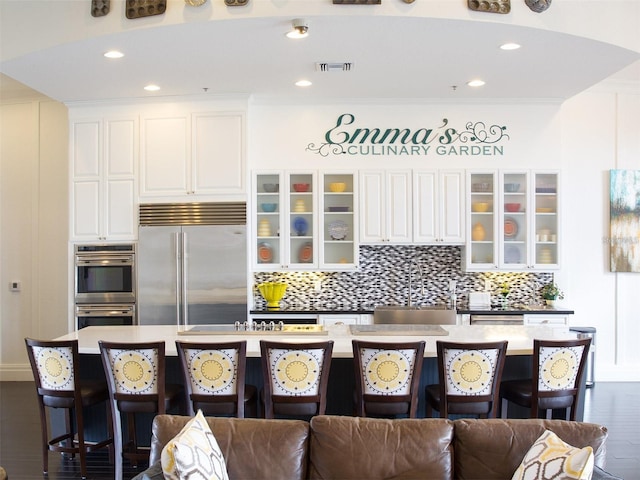 kitchen with sink, stainless steel appliances, white cabinetry, and an island with sink