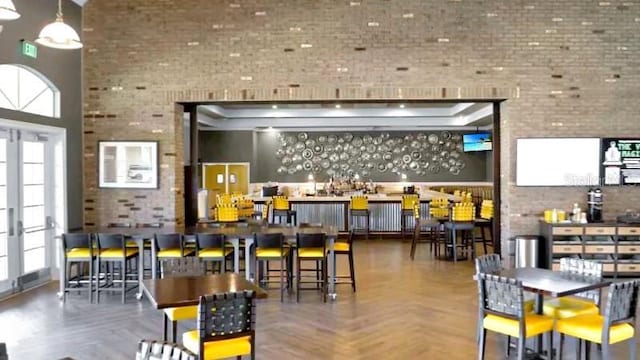 bar featuring parquet flooring, french doors, brick wall, and a high ceiling