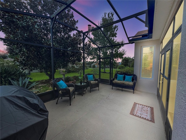 patio terrace at dusk with grilling area, a lanai, and an outdoor living space