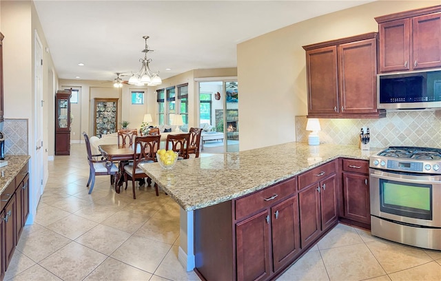 kitchen with light tile patterned floors, stainless steel appliances, hanging light fixtures, and kitchen peninsula