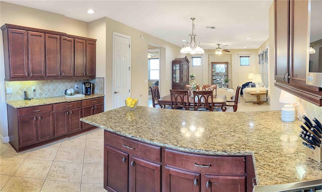 kitchen featuring light tile patterned floors, pendant lighting, backsplash, and light stone counters