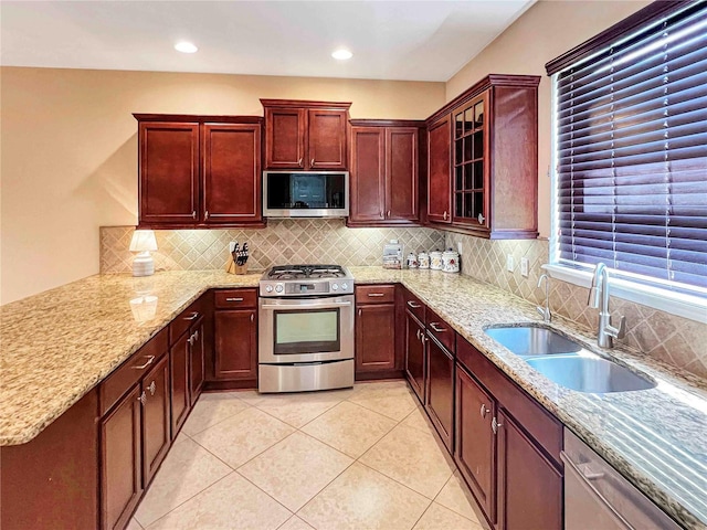 kitchen featuring light tile patterned floors, sink, light stone counters, stainless steel appliances, and decorative backsplash