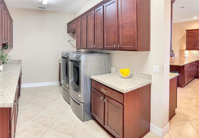 laundry room featuring light tile patterned floors, washer and clothes dryer, and cabinets