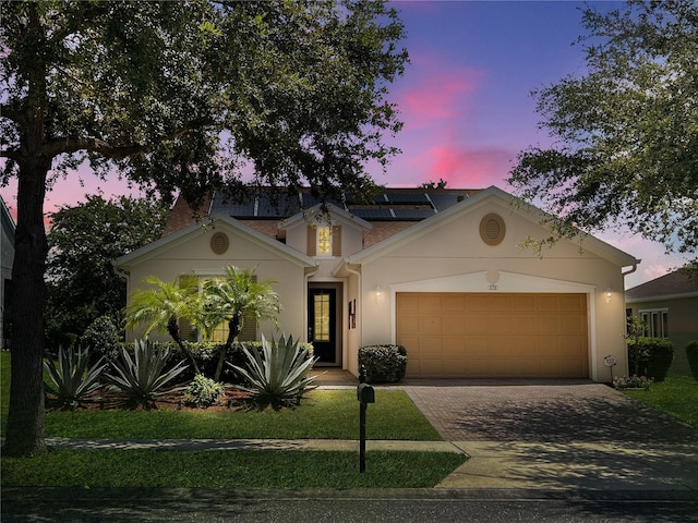 172 Balmy Coast Rd, Groveland, FL 34736 - view of front of house featuring driveway, a garage, stucco siding, and roof mounted solar panels