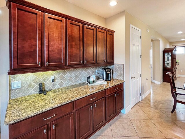 172 Balmy Coast Rd, Groveland, FL 34736 - kitchen with backsplash, reddish brown cabinets, light stone counters, light tile patterned floors, and recessed lighting