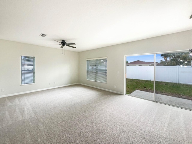 carpeted spare room with a ceiling fan, visible vents, and baseboards