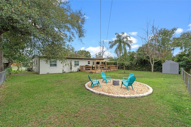 view of yard featuring a fire pit, a wooden deck, and a storage shed