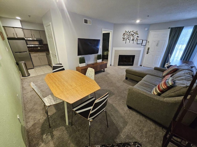 living room with light colored carpet and a tiled fireplace