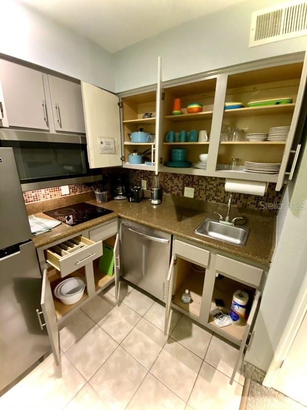 kitchen featuring stainless steel appliances, backsplash, light tile patterned floors, sink, and white cabinetry