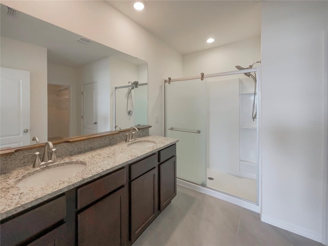 bathroom with double vanity, a stall shower, a sink, and a walk in closet